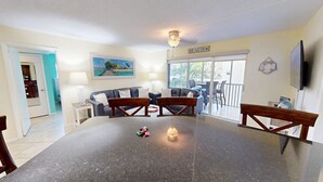 A dining area with a large table, two sofas, and a TV. - Crescent Arms Vacation Rentals 205N Siesta Key Florida (Siesta Key)