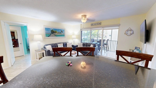 A dining area with a large table, two sofas, and a TV.