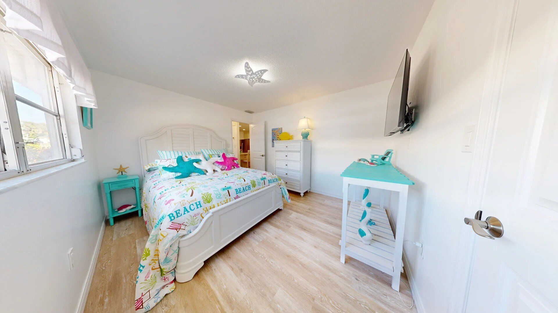 Une chambre à coucher comprenant un lit, une table de chevet, une commode, un bureau et un téléviseur fixé au mur.