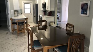 A modern kitchen with white cabinets, a dining table with chairs, and a refrigerator. - CAV15 (Siesta Key)