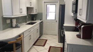 A kitchen with white cabinets, a sink, a microwave, and a refrigerator. - CAV15 (Siesta Key)