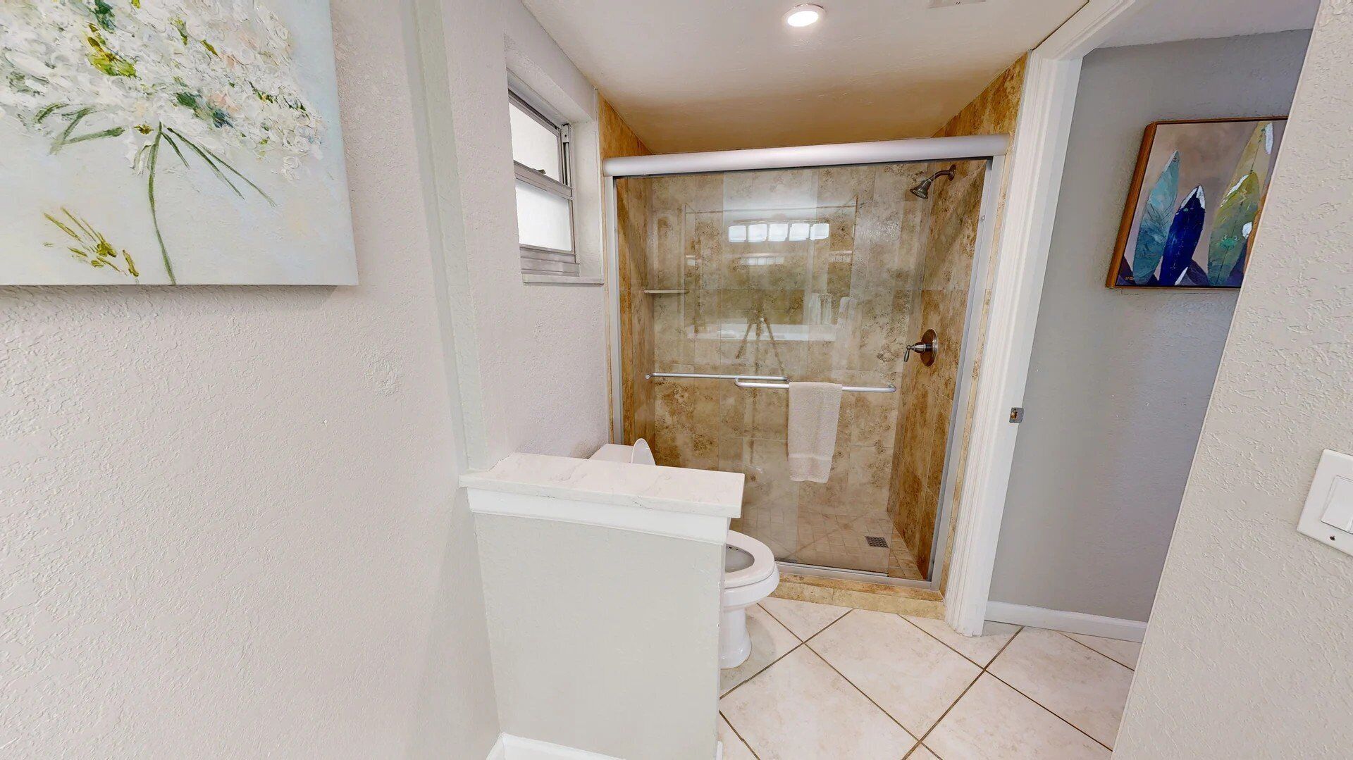 A bathroom with a glass shower enclosure, a toilet, and a sink.