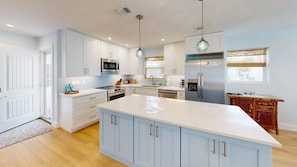 A modern kitchen with white cabinetry, a central island, stainless steel appliances, and pendant lighting. - Crescent Arms Villa 10 Siesta Key Florida (Siesta Key)