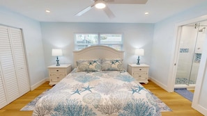 A bedroom with a bed, nightstands, a ceiling fan, a window, and a door leading to a bathroom. - Crescent Arms Villa 10 Siesta Key Florida (Siesta Key)
