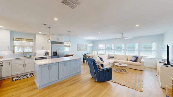 A spacious living area with a kitchen, dining area, and seating with a view of the outdoors.