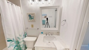 A bathroom with a toilet, a sink, a mirror, and a shower curtain.