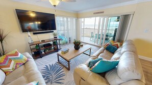 A living room with a sofa, coffee table, TV, and a balcony with a view. - Crescent Arms Vacation Rentals 204N Siesta Key Florida DISCOUNTS! (Siesta Key)