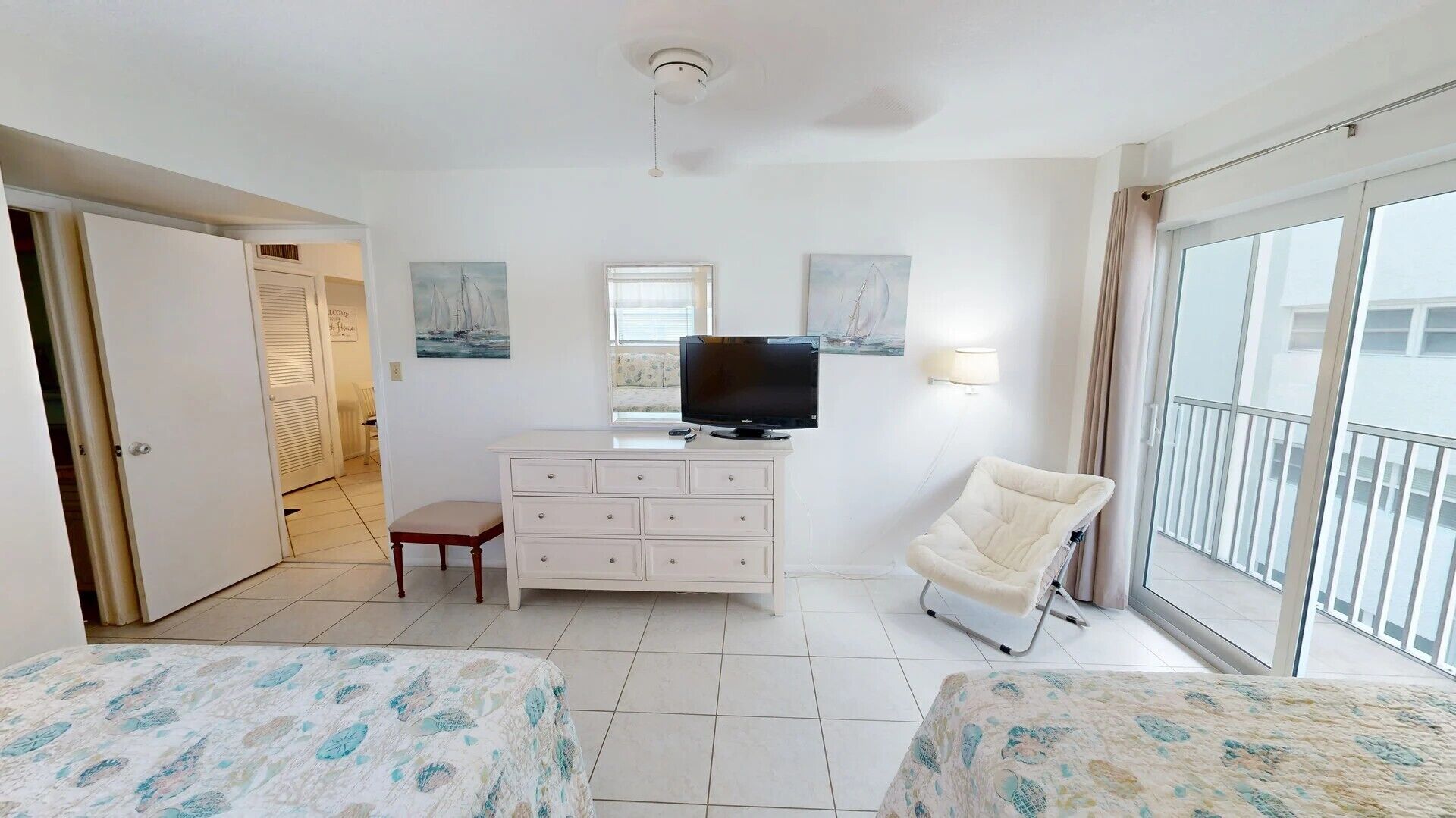 A hotel room with a bed, a TV, a chair, a dresser, and a balcony.