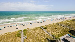 A beach with a wooden boardwalk, beach umbrellas, and a clear view of the ocean. - Octopus Garden: 1BR, King Bed, Indoor/Outdoor Pool (Carolina Beach)