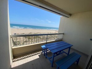 Enjoy the ocean view from this balcony with a table and two benches.