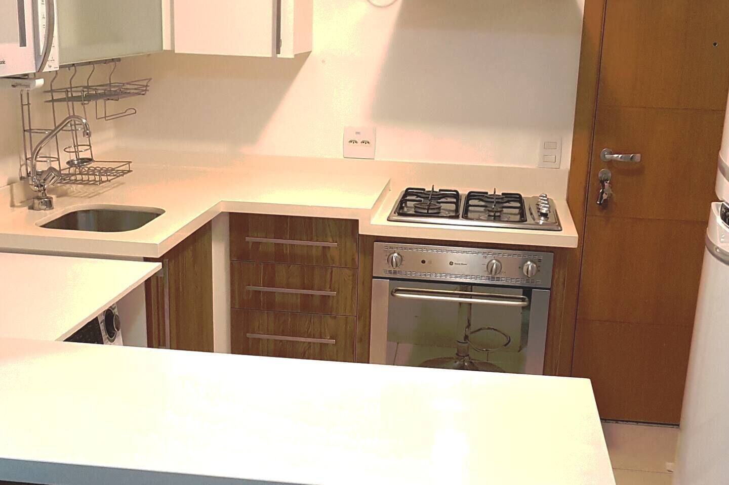 A compact kitchen with a sink, stove, oven, and wooden cabinets.