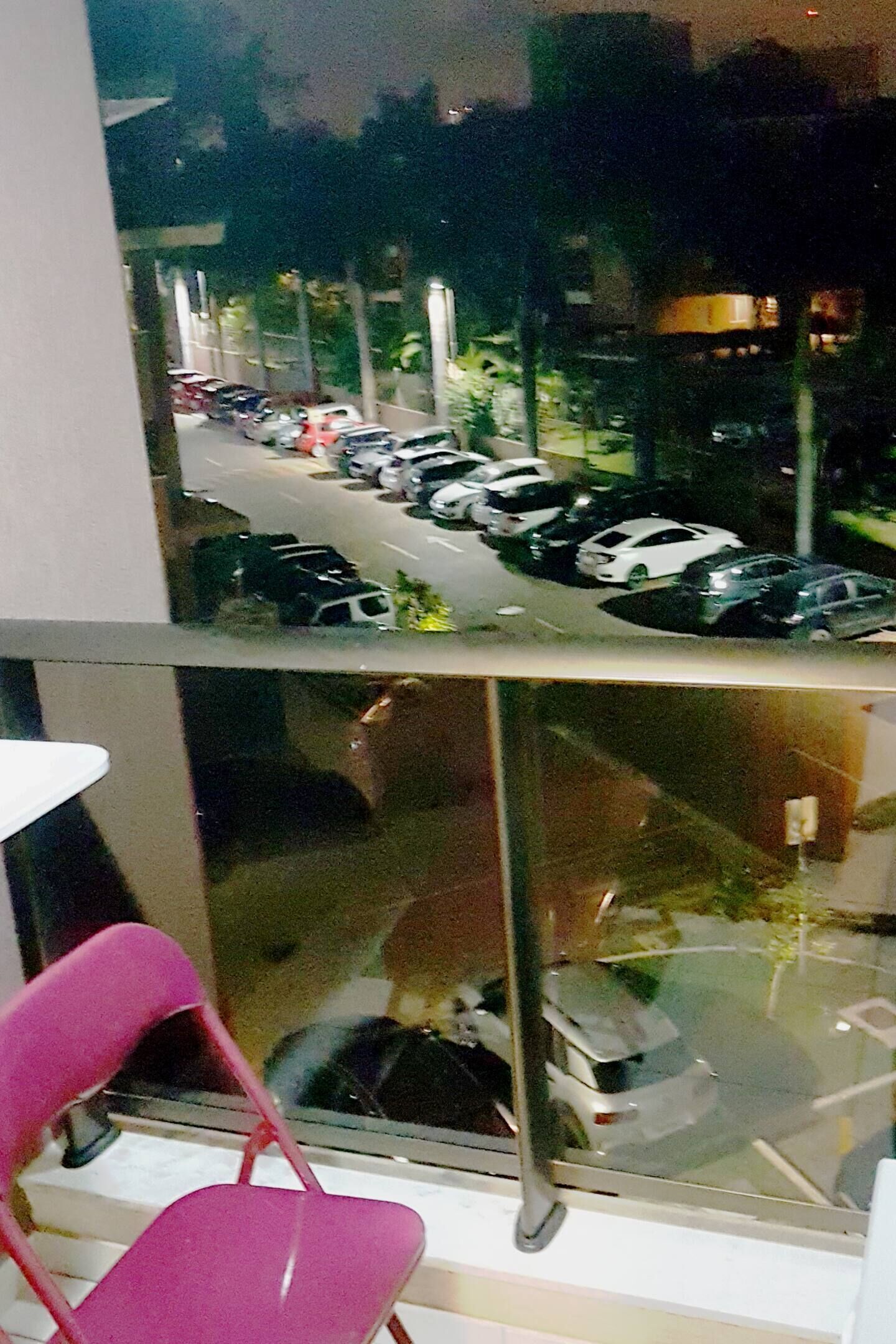 Blick aus einem Fenster auf einen Parkplatz mit mehreren parkenden Autos.