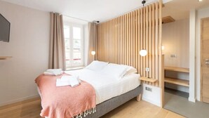 Une chambre moderne avec un lit, une cloison en bois et un téléviseur fixé au mur.