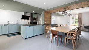 Une cuisine moderne avec des meubles de couleur bleu clair, un îlot central et un coin repas doté de chaises en bois.