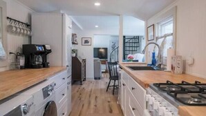 A compact kitchen with a washing machine, a coffee machine, and a stove. - Hadley Hideaway Cottage (Hadley)