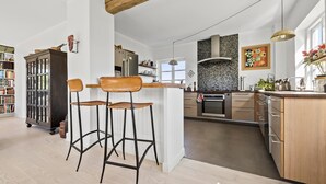 Une cuisine moderne dotée d’un îlot central, de tabourets de bar, d’un meuble en bois et d’un pare-feu en carrelage.