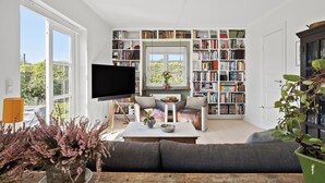 Un salon comprenant une grande bibliothèque, un téléviseur à écran plat, un canapé et une table basse.