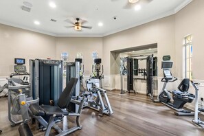 A gym with various exercise machines, a treadmill, and a mirrored wall.