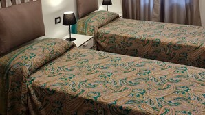 Ein Hotelzimmer mit zwei Betten, einem Stadtbild an der Wand, einem Fenster mit Vorhängen und Nachttischlampen.