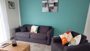 A living room with a grey sofa, a wooden coffee table, and teal walls. - Gite DU Vieux Chene (Reignac)