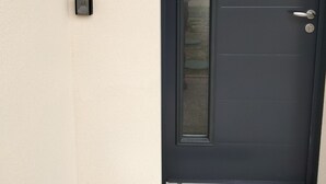 A dark-colored door with a glass panel and a small mailbox on the wall to the left. - Gite DU Vieux Chene (Reignac)