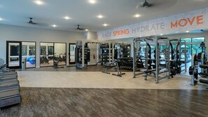 Ein Fitnessraum mit Cardiogeräten, Krafttrainingsgeräten und einer Spiegelwand.