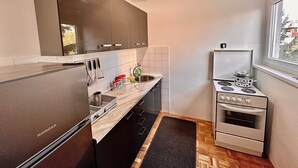 Une cuisine compacte dotée d’appareils électroménagers modernes, notamment un réfrigérateur, une cuisinière et un évier.
