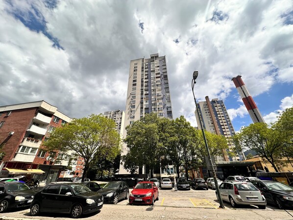 Un estacionamiento con varios coches, un edificio alto al fondo y una farola.