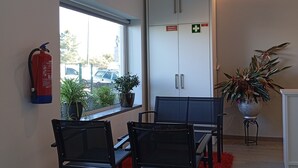 A conference room with a table and chairs, a fire extinguisher, a potted plant, and a cabinet with signs. - Casa Talika (Ourem)