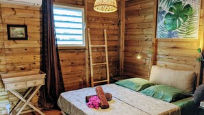 Una habitación de cabaña de madera con una cama, un escritorio, una escalera y una ventana.