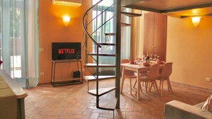 A spiral staircase, a dining area with chairs and a table, and a television with 'NETFLIX' on it. - The Painter's Nest + Lake Garden (Cima)