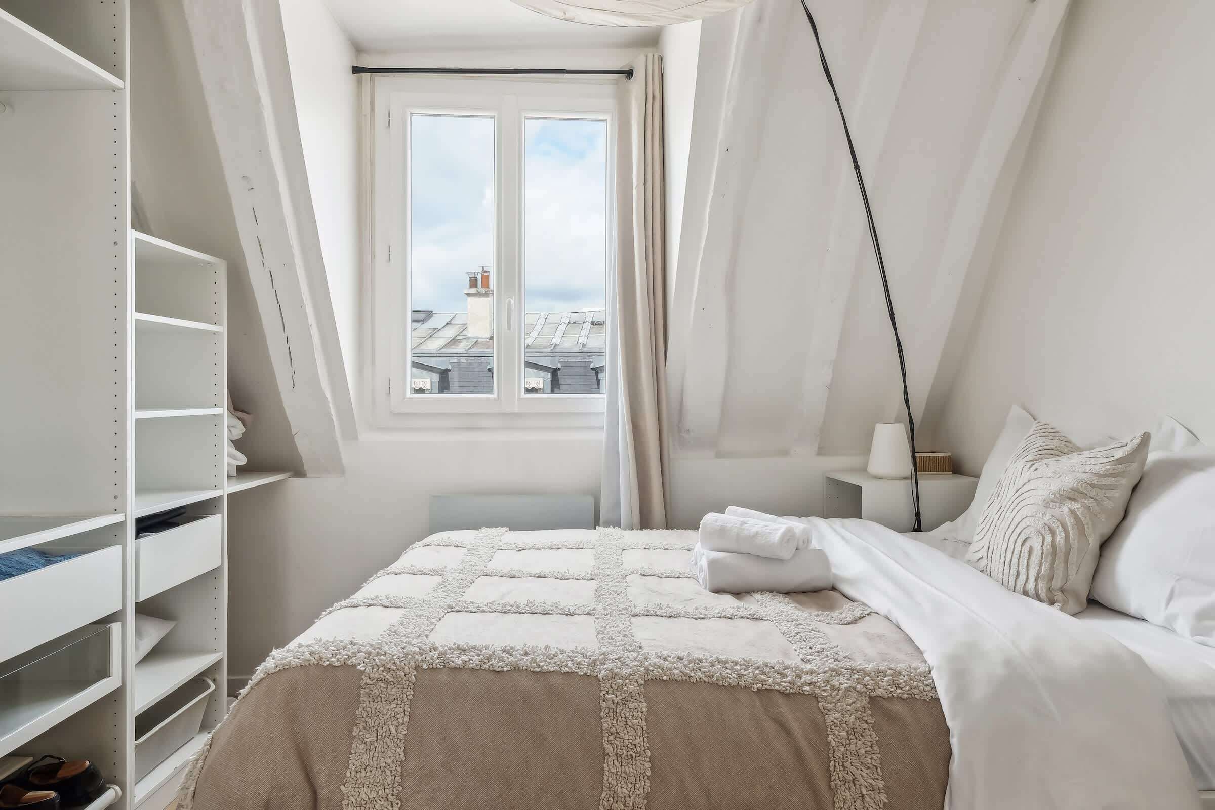 A bedroom with a bed, a window, and a closet.