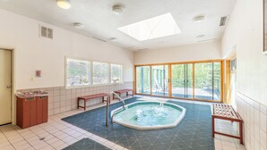 A spacious indoor swimming pool with clear views of the outdoors, a skylight, and a tiled floor.