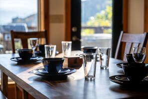 Una mesa de comedor dispuesta con varios vasos y cuencos, con vista al exterior a través de una ventana.