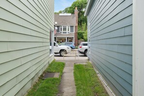A narrow alleyway between two houses with a pathway leading to a garage. - La Maison on Main with views of the Harbor Point and a Private Courtyard! (Harbor Springs)