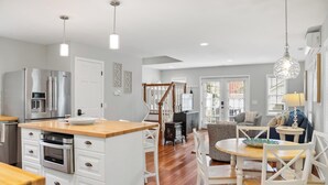 Una cocina moderna con una isla central, electrodomésticos de acero inoxidable y un comedor con una mesa redonda y sillas.