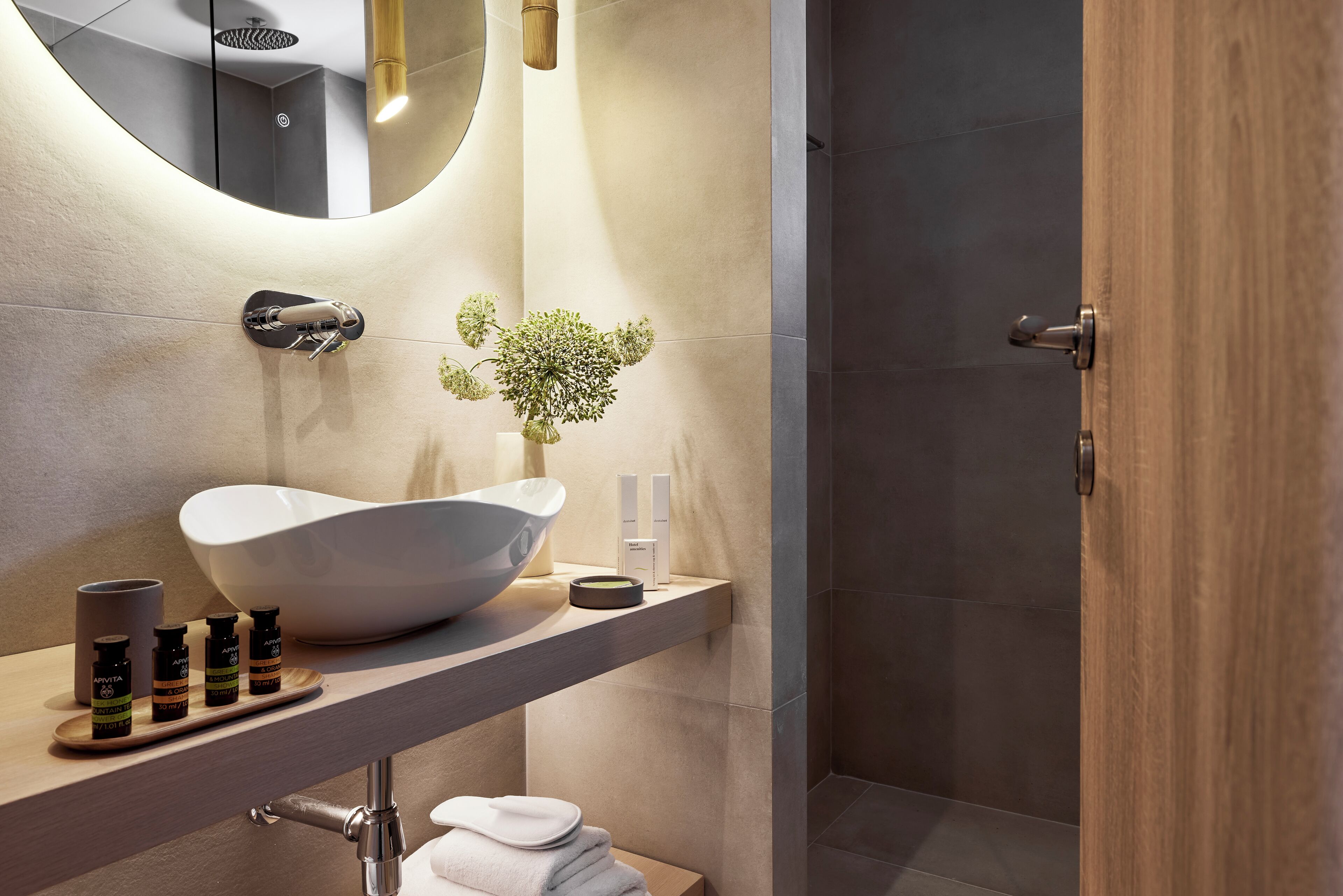 A modern bathroom with a large white basin, a mirror, and a wooden door.