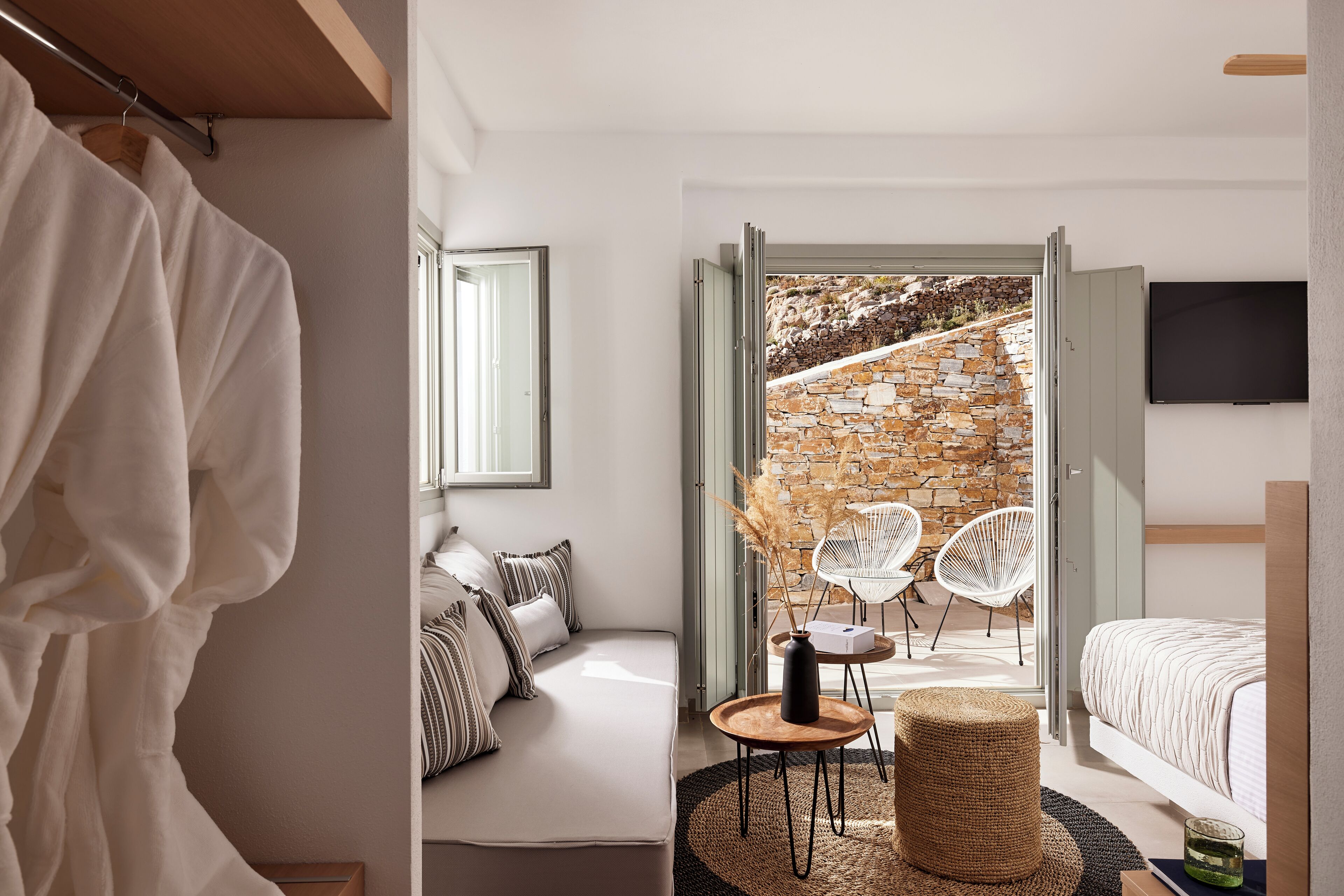 Un dormitorio moderno con pared de piedra, un sofá, una cama y un televisor.