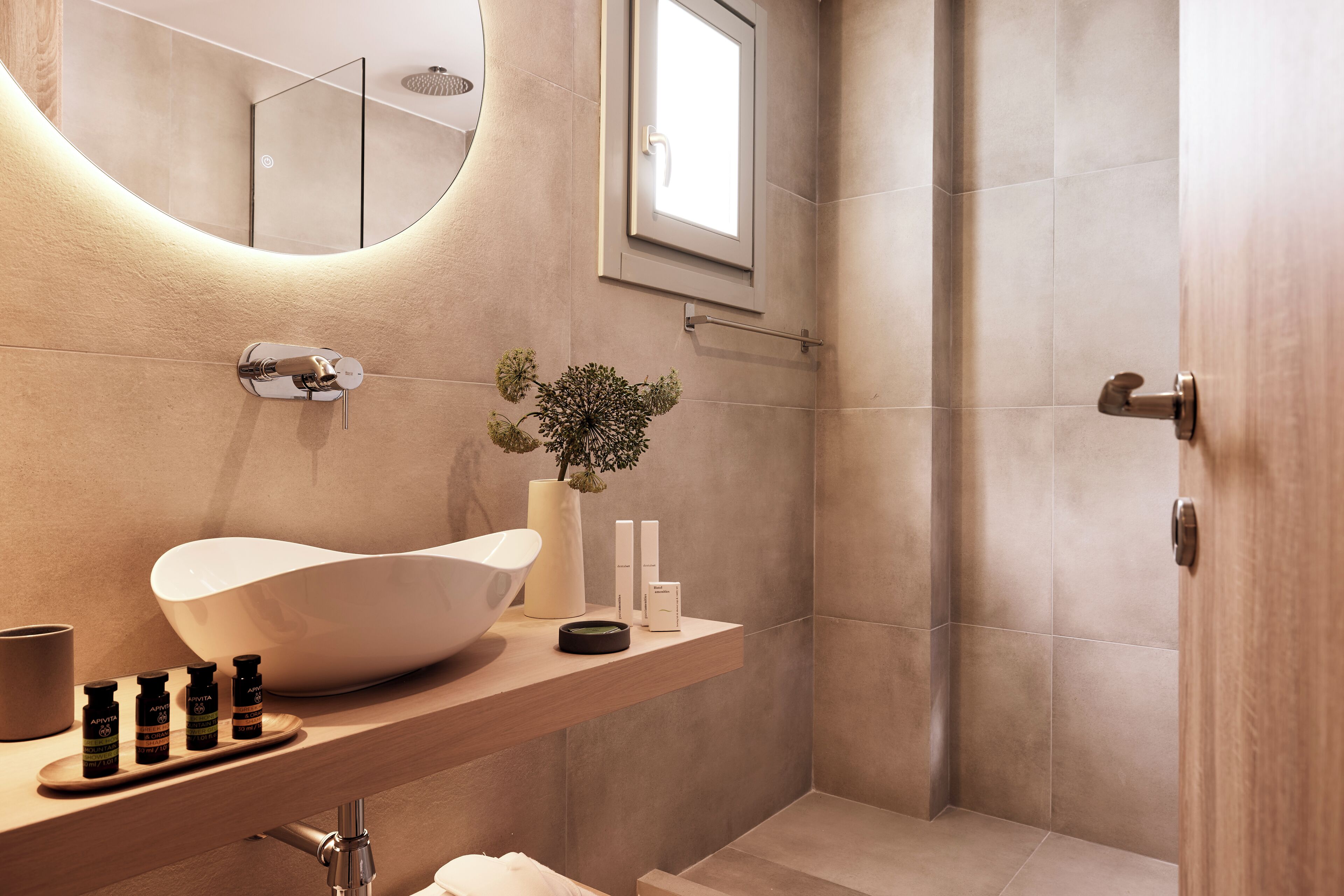 A modern bathroom with a large sink, a mirror, and a shower area.