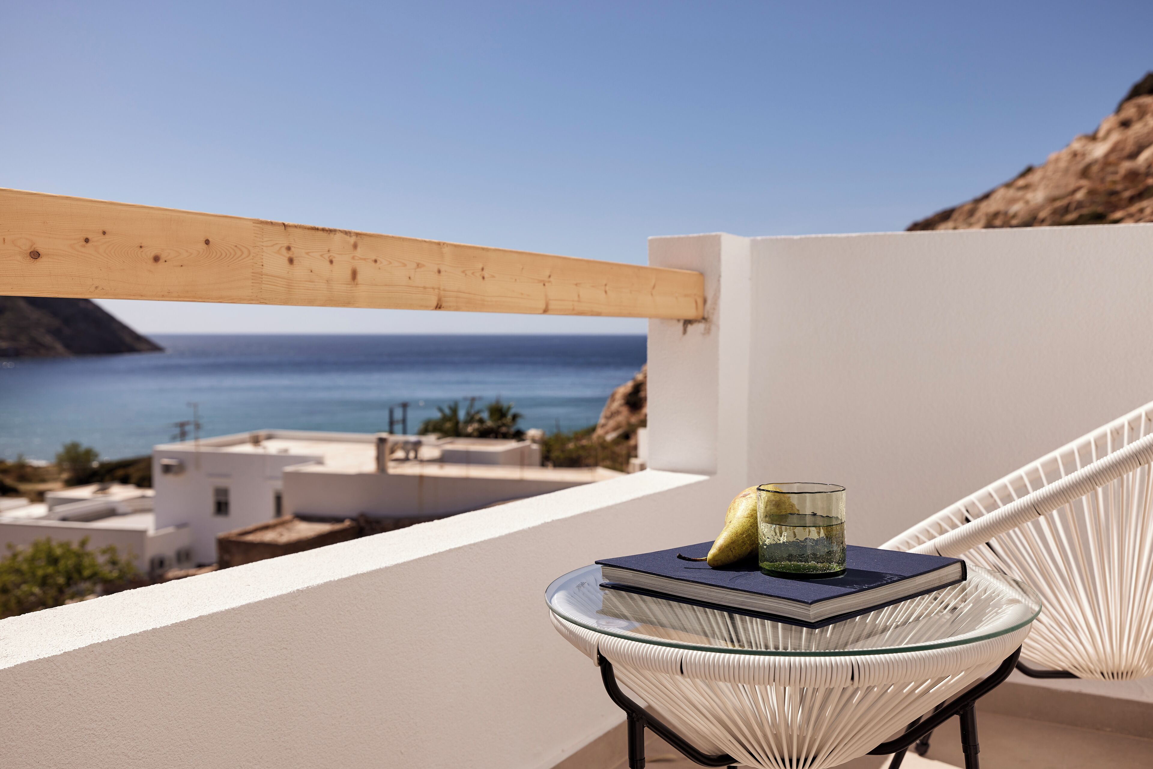 Ein Balkon mit einem Glastisch, einem Buch und einem Glasbehälter.
