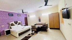 Une chambre à coucher comprenant un lit, un canapé, une télévision, une armoire et un ventilateur de plafond.