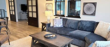A living room with a sofa, coffee table, and artwork on the wall.