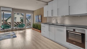 Eine moderne Küche mit weißen Schränken, einem Backofen von Bosch und einem großen Fenster mit Blick auf eine Terrasse.