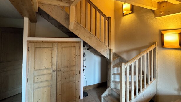 Un interior de madera con una escalera, una puerta de madera y una mesa.