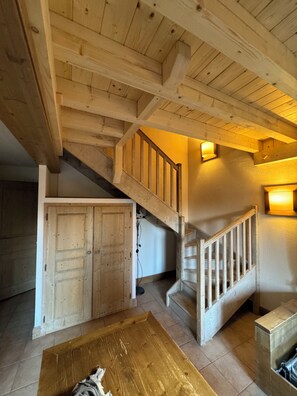 Een houten interieur met een trap, een houten deur en een tafel.