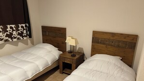 Dos camas individuales con cabeceros de madera y una mesita de noche con lámpara entre ellas.