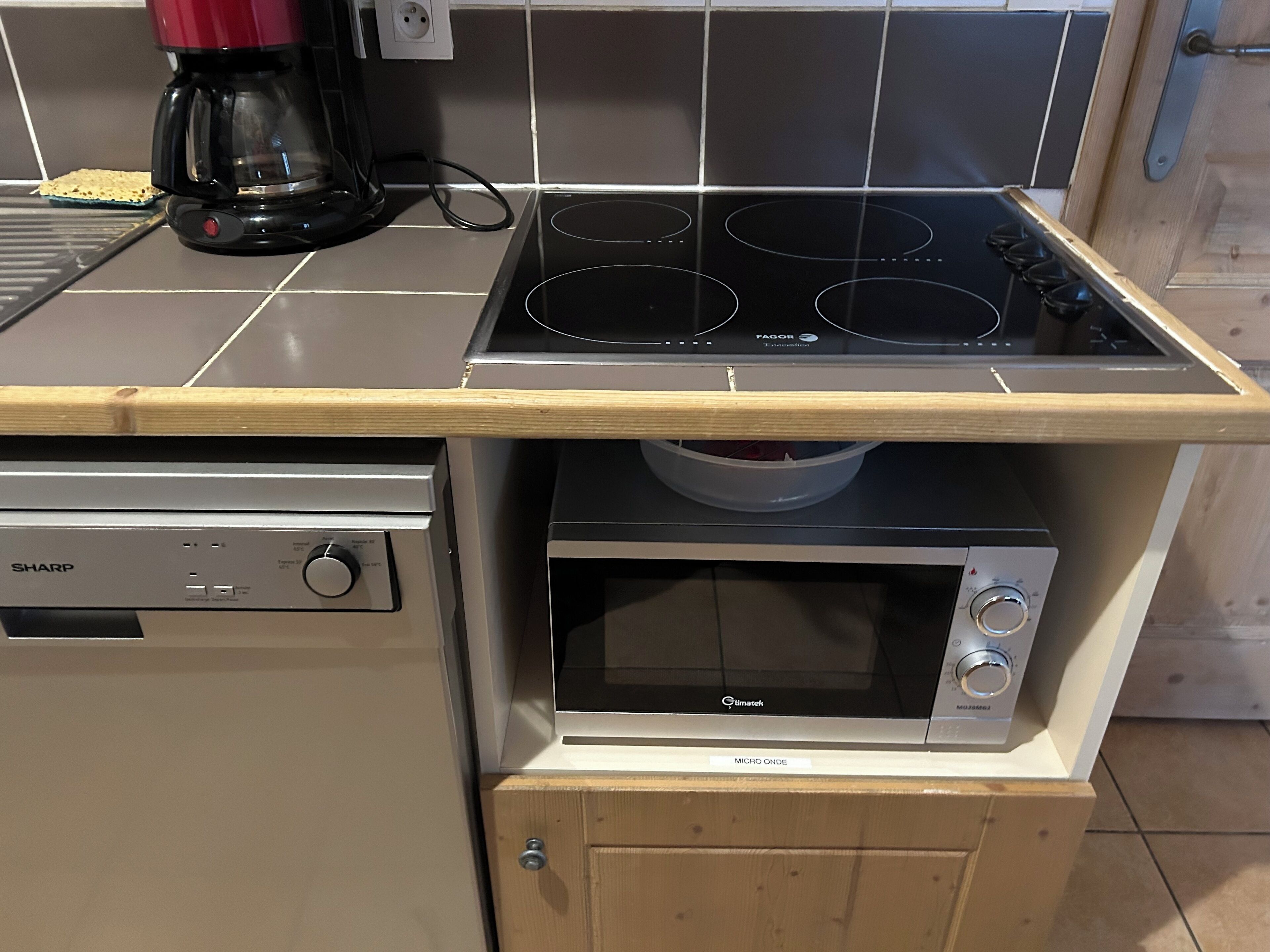 A compact kitchen with a built-in microwave, a stovetop, and a dishwasher.