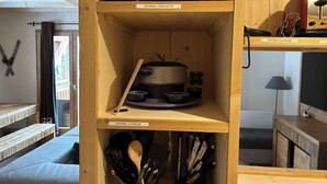 Un armario de cocina de madera con estantes identificados para utensilios de cocina.