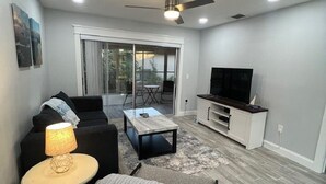Un salon moderne comprenant un canapé, une table basse, un meuble pour la télévision et un ventilateur de plafond.