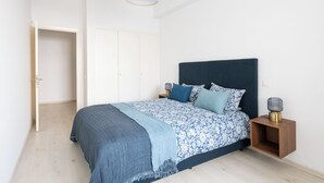 A bedroom with a bed, bedside tables, a wardrobe, and a hanging lamp. - Charming apartment, in the heart of Agdal, 2 rooms (Rabat)